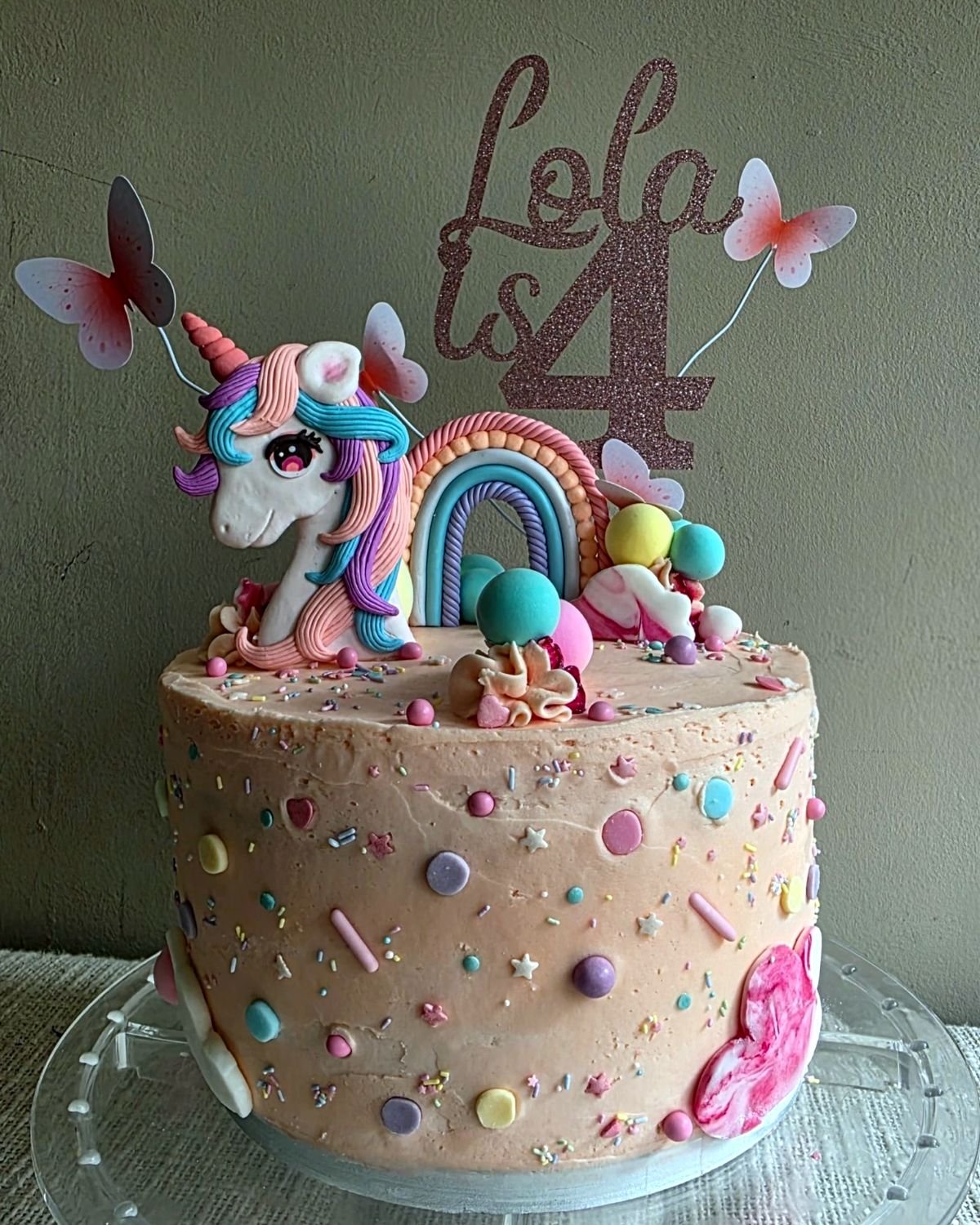 Pink birthday cake with a sugar unicorn, rainbow and sprinkles