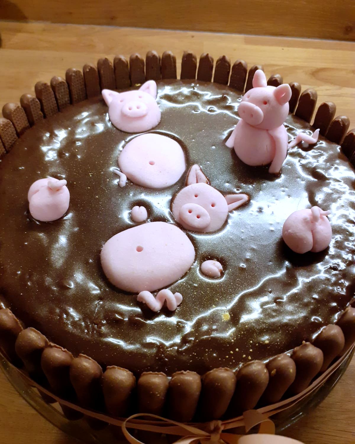 Chocolate cake ringed with chocolate fingers, with sugar pigs in a chocolate mud bath